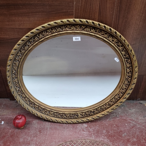 304 - A heavy vintage oval mirror housed in a gilt frame. MM: 70cm x 60cm.