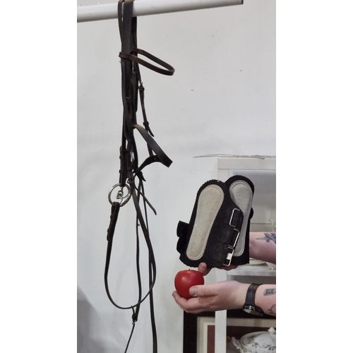 357 - A quality leather pony bridle and snaffle bit with reins. Includes a pair of brushing boots.