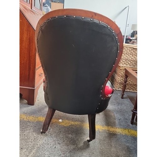 415 - Star Lot : A Victorian button-tufted slipper chair with curved mahogany frame, black leather upholst... 