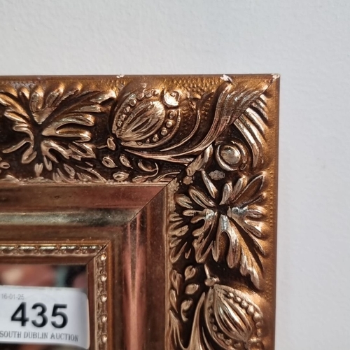 435 - A carved giltwood mirror featuring floral motifs in a baroque-inspired frame.