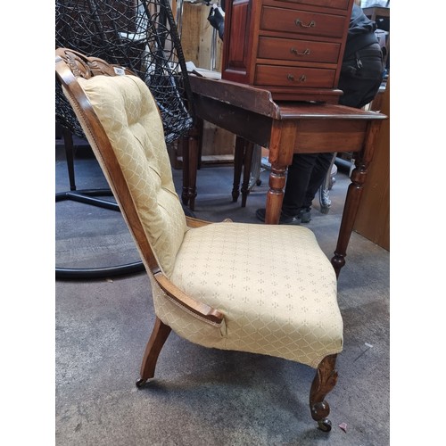 367 - An antique nursing chair featuring a carved oak wood frame, button back with braiding mounted on cas... 