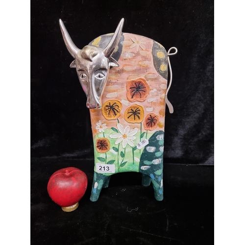 213 - A folk art style cow figurine with highly textured hand painted design and chrome face.