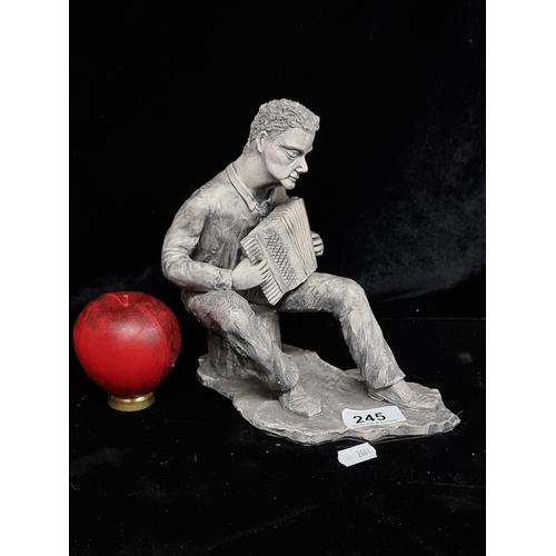 245 - A cast metal figure of a seated man playing the accordian.