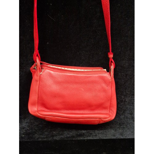 260 - A fashionable Radley bright red leather hand bag. With the iconic Scottie dog tag.