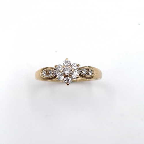 28 - Star Lot : An attractive daisy diamond ring with diamond shoulders set in nine carat gold. 'DIA' mar... 