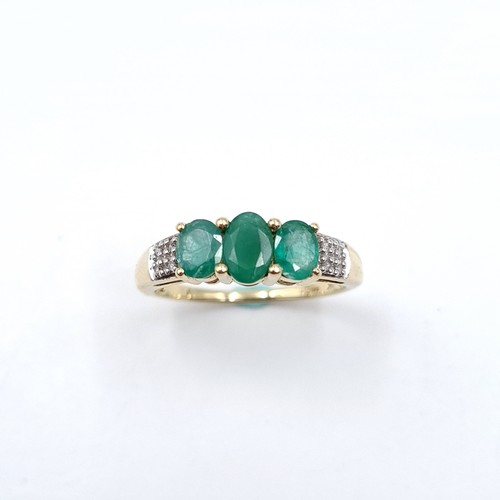 46 - Star lot : A nice example of a nine carat gold three stone emerald ring with diamond surround. Size ... 