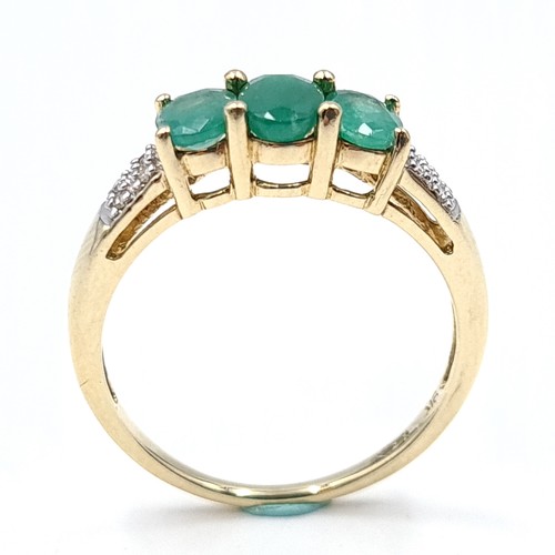 46 - Star lot : A nice example of a nine carat gold three stone emerald ring with diamond surround. Size ... 