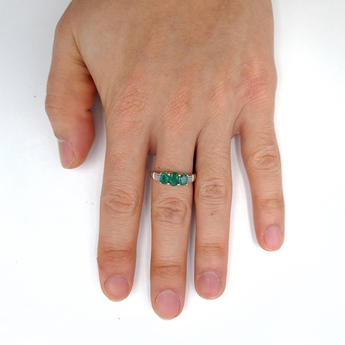 46 - Star lot : A nice example of a nine carat gold three stone emerald ring with diamond surround. Size ... 