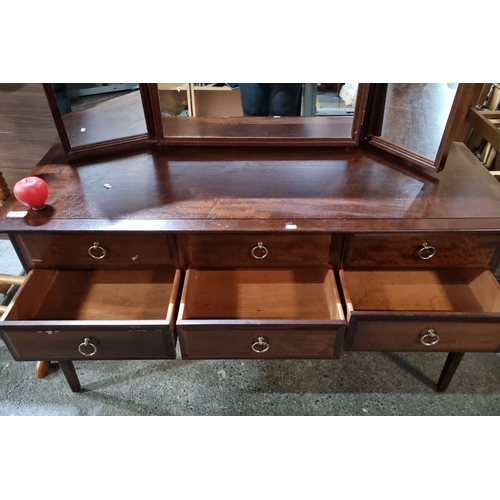 589 - A vintage Stag furniture mahogany vanity dresser with tri-fold mirror, six drawers, and brass ring p... 