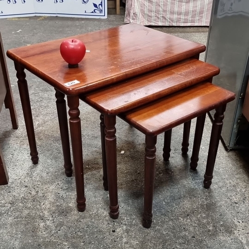 620 - A set of mahogany nesting tables featuring solid wood construction with turned legs and a rich, warm... 