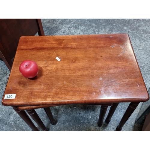 620 - A set of mahogany nesting tables featuring solid wood construction with turned legs and a rich, warm... 