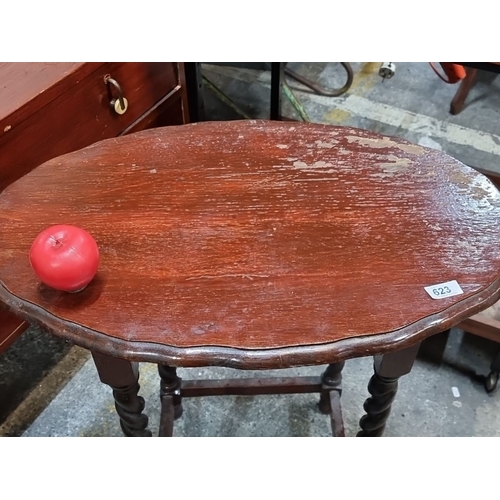 623 - An Early 20th-century oak side table with barley twist legs, scalloped oval top, and stretcher base.... 