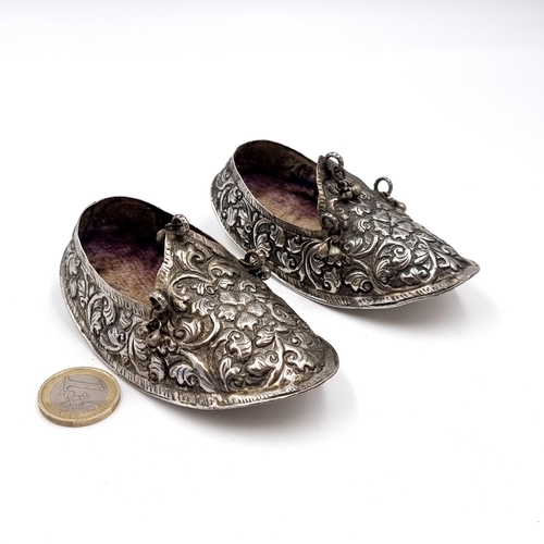 12 - A pair of antique silver shoes set with cloth inlay with repousse detailing. Hallmarks to base but i... 