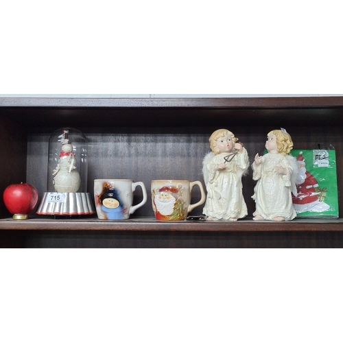 715 - A selection of Christmas decorations including two mugs, porcelain angels and Santa napkins.