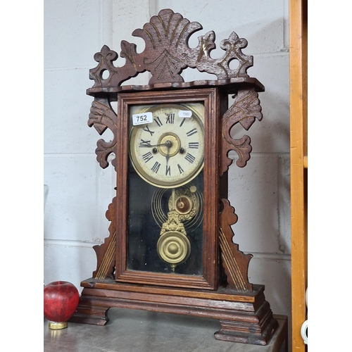 752 - An Ansonia Clockmaking Company 8 day gingerbread mantel clock housed in a carved oak case with roman... 