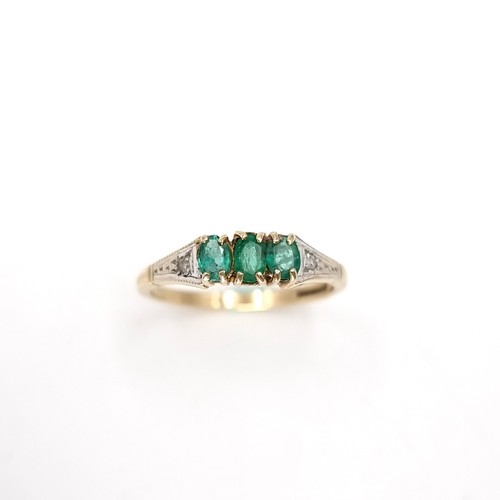 24 - Star Lot : A three stone nine carat gold 375 emerald ring with diamond set shoulders. Ring size - O.... 