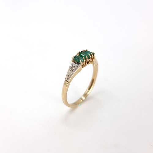 24 - Star Lot : A three stone nine carat gold 375 emerald ring with diamond set shoulders. Ring size - O.... 