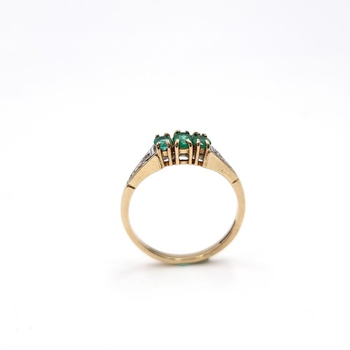 24 - Star Lot : A three stone nine carat gold 375 emerald ring with diamond set shoulders. Ring size - O.... 