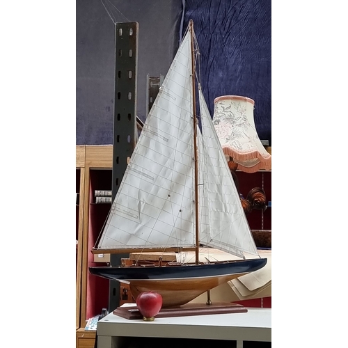 441 - A large Wooden sailboat model features detailed rigging and deck, mounted on a display stand. Approx... 