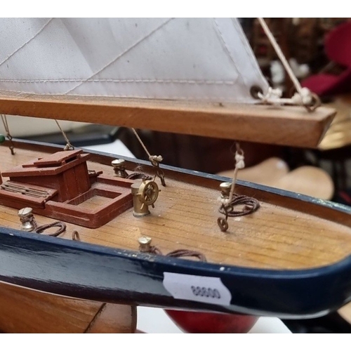 441 - A large Wooden sailboat model features detailed rigging and deck, mounted on a display stand. Approx... 