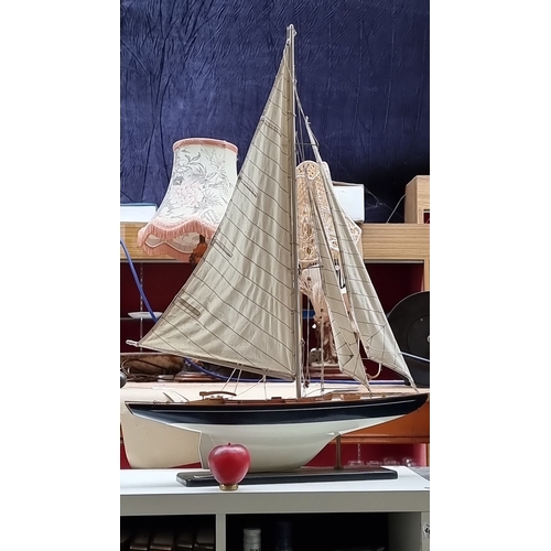 442 - A large Wooden sailboat model on a black stand. Features detailed rigging, cloth sails, and realisti... 