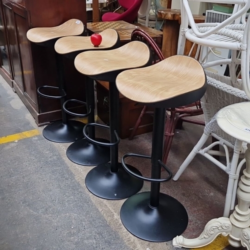 475 - Set of four as new modern adjustable bar stools with curved wood seats, black metal bases, and integ... 