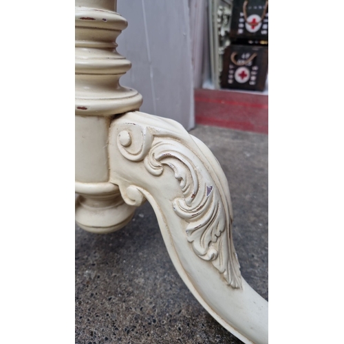 476 - Ornately carved pedestal table, vintage cream-painted finish with intricate scroll details, tripod b... 