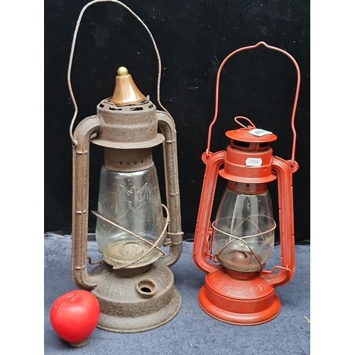 484 - Rustic early 20th-century kerosene lanterns feature embossed glass with a bat motif and a vibrant re... 