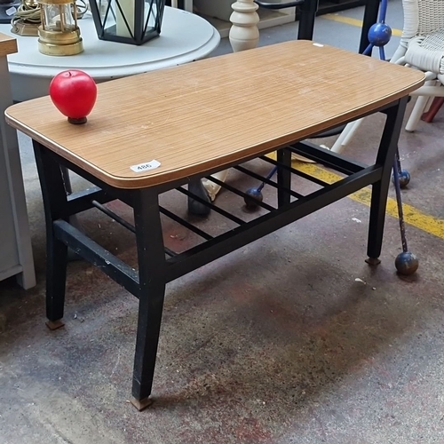 486 - Coffee table with wood-grain laminate top, black metal frame, and lower metal rack.