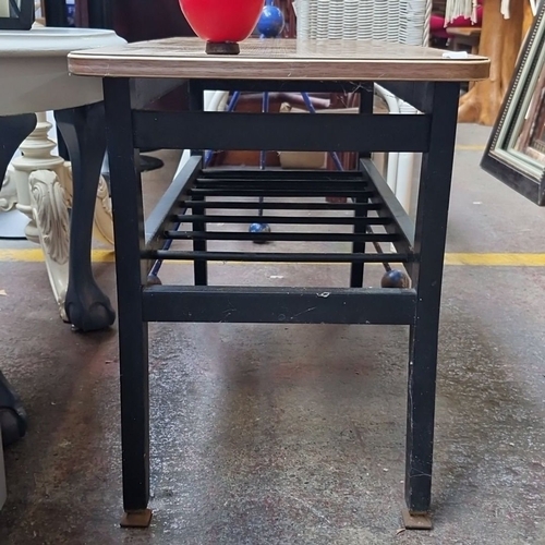 486 - Coffee table with wood-grain laminate top, black metal frame, and lower metal rack.