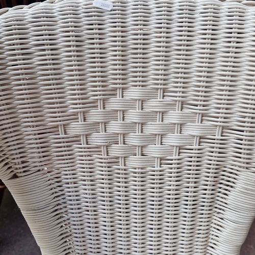 489 - Pair of white wicker chairs featuring classic woven designs.