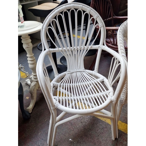 489 - Pair of white wicker chairs featuring classic woven designs.