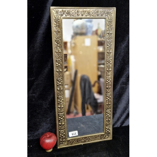 315 - A vintage wall mirror housed in an embossed metal frame featuring floral detailing in low relief and... 