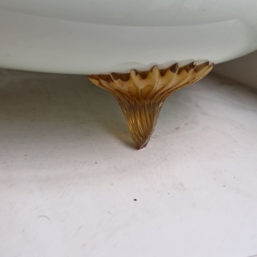 695 - A large Vintage opaline glass bowl with scalloped rim, supported by three amber-hued glass feet. Fro... 