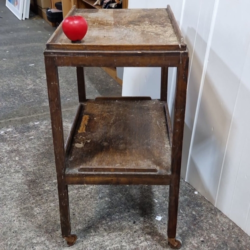 953 - Vintage wooden two-tier serving trolley on castors. Displays a well-worn patina with visible surface... 