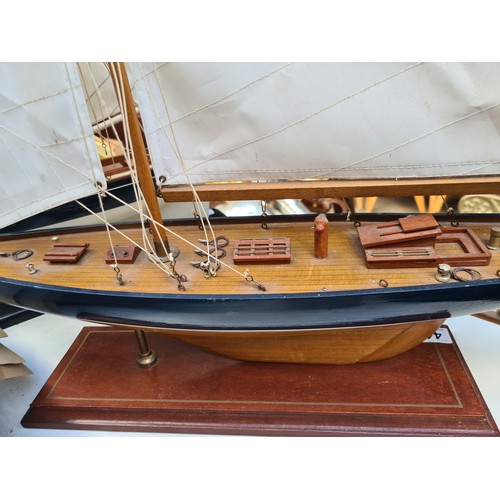 441 - A large Wooden sailboat model features detailed rigging and deck, mounted on a display stand. Approx... 