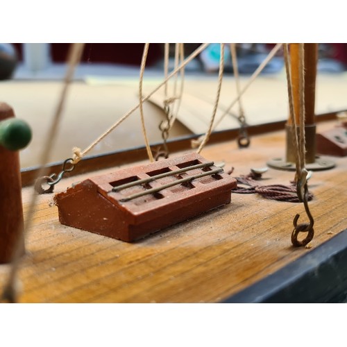 441 - A large Wooden sailboat model features detailed rigging and deck, mounted on a display stand. Approx... 