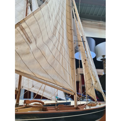 442 - A large Wooden sailboat model on a black stand. Features detailed rigging, cloth sails, and realisti... 