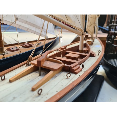 442 - A large Wooden sailboat model on a black stand. Features detailed rigging, cloth sails, and realisti... 