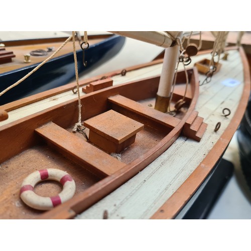 442 - A large Wooden sailboat model on a black stand. Features detailed rigging, cloth sails, and realisti... 