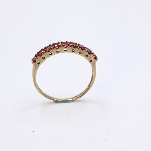 583 - Star Lot : A nine carat gold half eternity ruby ring. Size - O. Weight - 1.27 grams. Boxed.