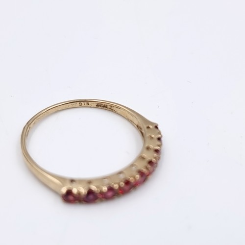 583 - Star Lot : A nine carat gold half eternity ruby ring. Size - O. Weight - 1.27 grams. Boxed.