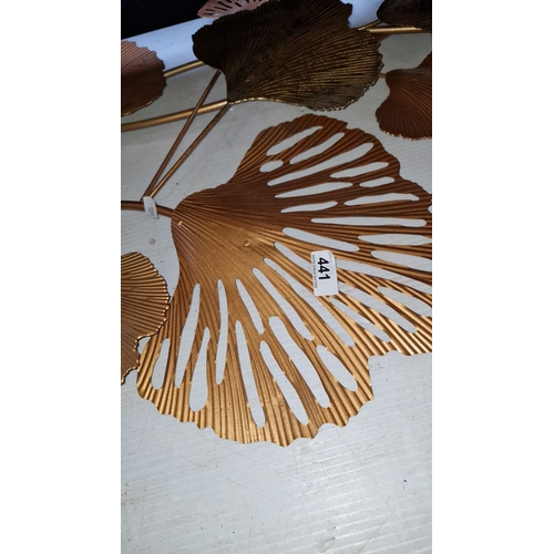 441 - A large decorative piece of metal wall art features an intricate, gold-toned ginkgo leaf design with... 