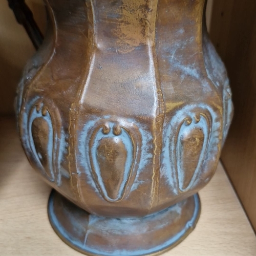 697 - Pair of antique brass and copper repousse water pitchers with ornate handles and fluted design.