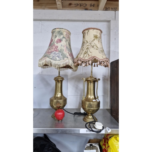 An impressive pair of antique brass urn shaped vases converted into table lamps fitted with floral and trim shades.