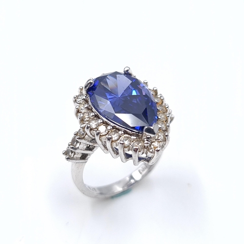 1408 - A large heavy striking sterling silver heart shaped blue gemstone ring with gem set surround. Size -... 