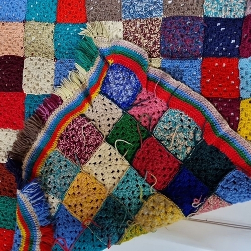 1132 - A Multicolored crochet patchwork blanket with vibrant fringe edging.