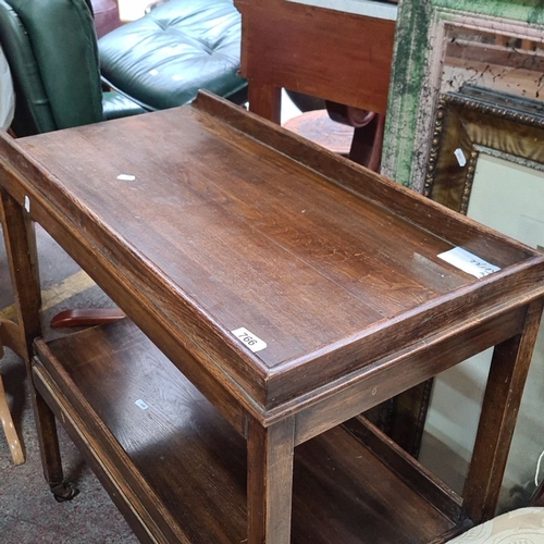 766 - Early 20th-century oak two-tier serving trolley with raised gallery edges and rolling casters.