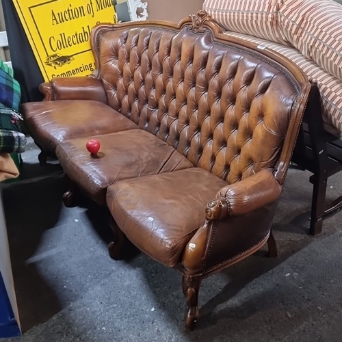 915 - Star lot :A Victorian-style button-tufted leather sofa with ornately carved wooden frame, rolled arm... 