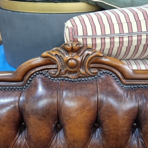 915 - Star lot :A Victorian-style button-tufted leather sofa with ornately carved wooden frame, rolled arm... 